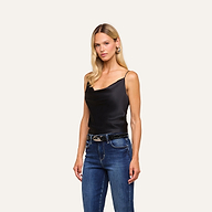A woman with long blonde hair wears the Calista Silk Camisole in black and blue jeans, standing against a plain light background.