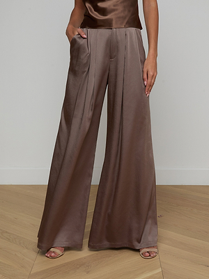 Wearing a wide-leg, high-waisted, brown satin trouser with pleats and the Calista Silk Camisole, paired with open-toe heels. The person stands on a light wood floor against a plain wall.