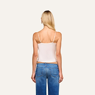 A woman with long blonde hair is seen from the back in the Calista Silk Camisole and blue jeans, standing against a plain light background.