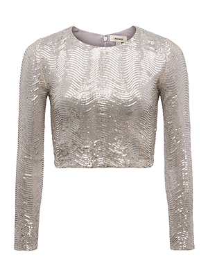 The L'AGENCE Rogan Sequin Cropped Top is a modern silver long-sleeved crop top with a round neck and wavy sequin pattern, ideal for parties; shown against a plain white background.