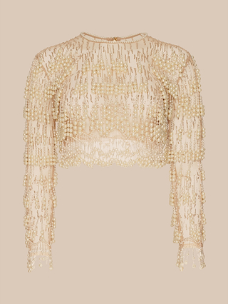 The Rogan Pearl Fringe Top is a sheer, long-sleeved cropped mesh style, featuring gold beading and delicate pearl embellishments that drape elegantly against a beige background—an eye-catching piece reminiscent of standout looks from NYFW Fall 2026.
