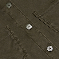 Close-up of the Isla Shirt in olive green featherweight twill, featuring two flap pockets and three four-hole metallic buttons engraved with small text around their edges.
