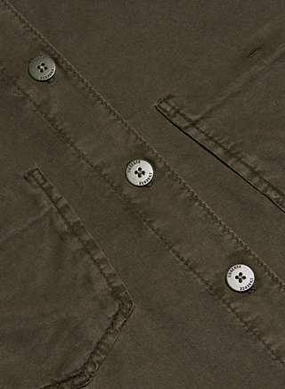 Close-up of the Isla Shirt in olive green, crafted from featherweight twill and featuring two angled pockets and three metallic four-hole buttons sewn onto the fabric. The stitching and texture of the material are clearly visible, echoing the signature style of L’AGENCE collared shirts.