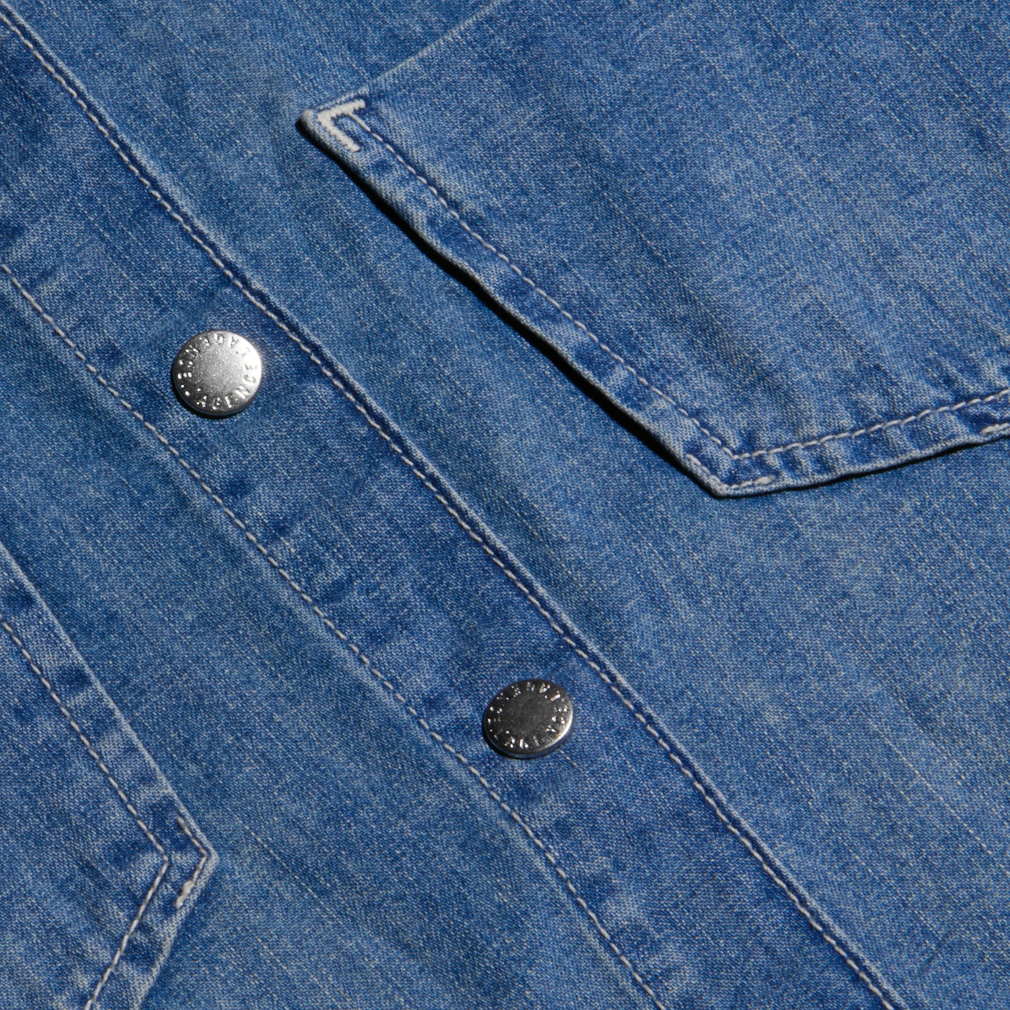 Close-up of the Isla Shirt in blue medium wash denim, featuring metal snap buttons and a visible pocket with detailed stitching.