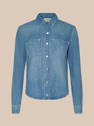 Front view of the Isla Shirt in blue featherweight denim, featuring silver buttons and two chest pockets, displayed on a solid beige background.