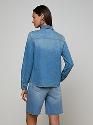 A woman stands with her back to the camera, wearing the lightweight Isla Shirt and matching denim shorts in an aged indigo wash, set against a plain off-white background.