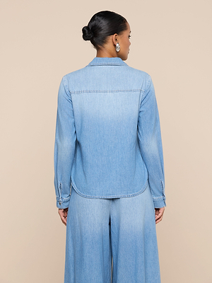 A person with hair in a neat bun is seen from behind, wearing the Isla Shirt and matching wide-legged denim pants against a beige background.