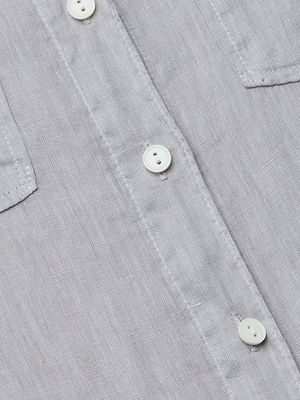 Close-up of the Isla Linen Shirt in light grey, featuring a button placket with white buttons and a partial view of the chest pocket. The linen fabric’s texture and fine stitching emphasize the quality of this classic shirt.