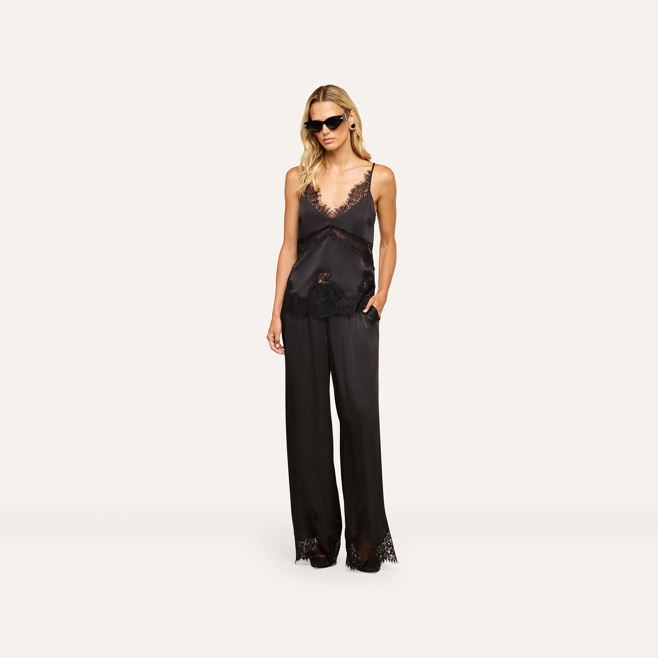 A woman wearing the Mitsu Satin Lace Camisole with matching wide-leg pants and sunglasses stands against a plain white background.