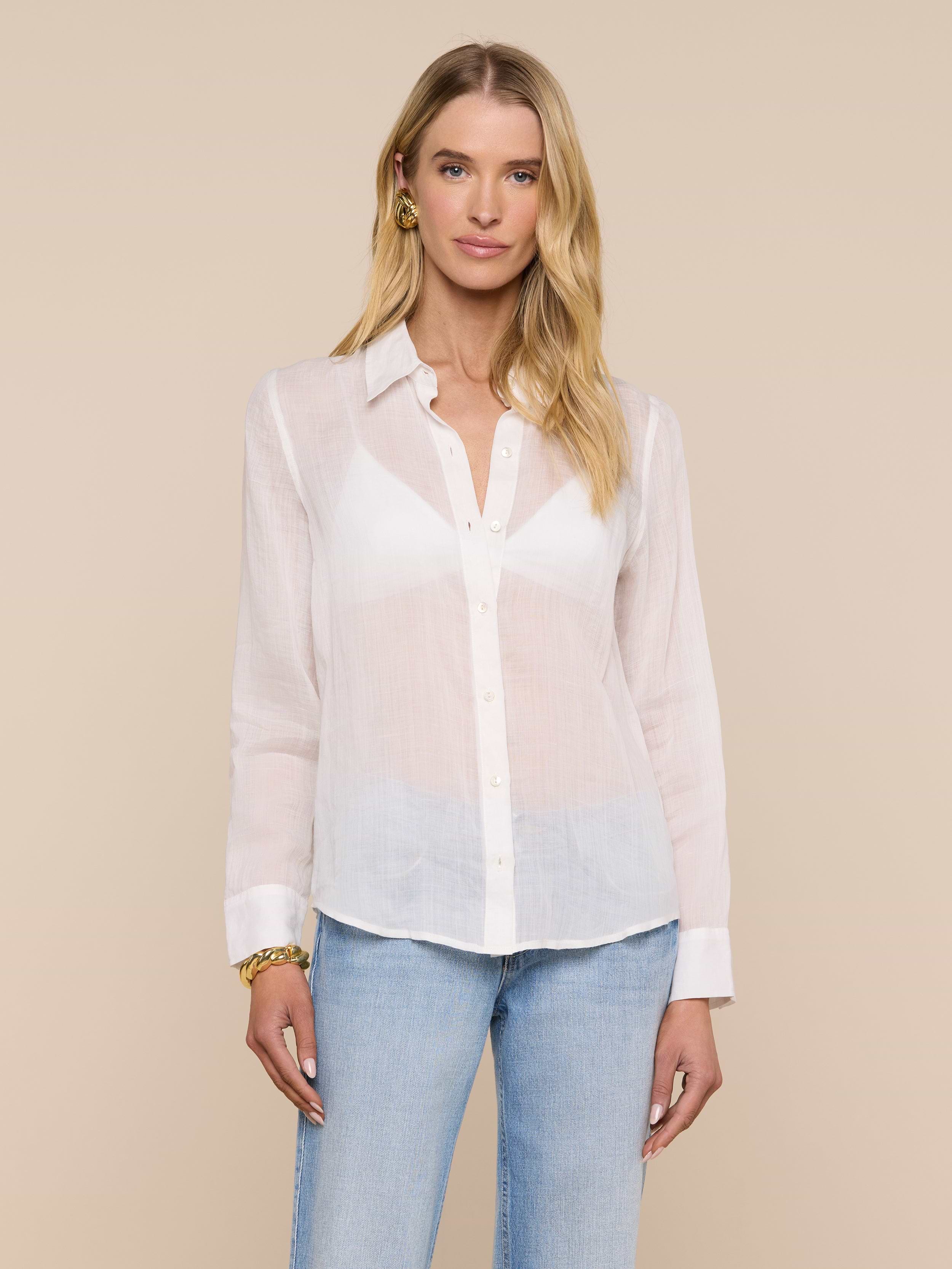 A woman with long blonde hair wears the Ellery Blouse and light blue jeans, standing against a plain, light background. She has minimal jewelry and a neutral expression.