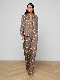 Wearing the Ellery Button-Down Shirt in taupe polka-dot, paired with a cropped tank and matching pants, a person stands against a plain white background.
