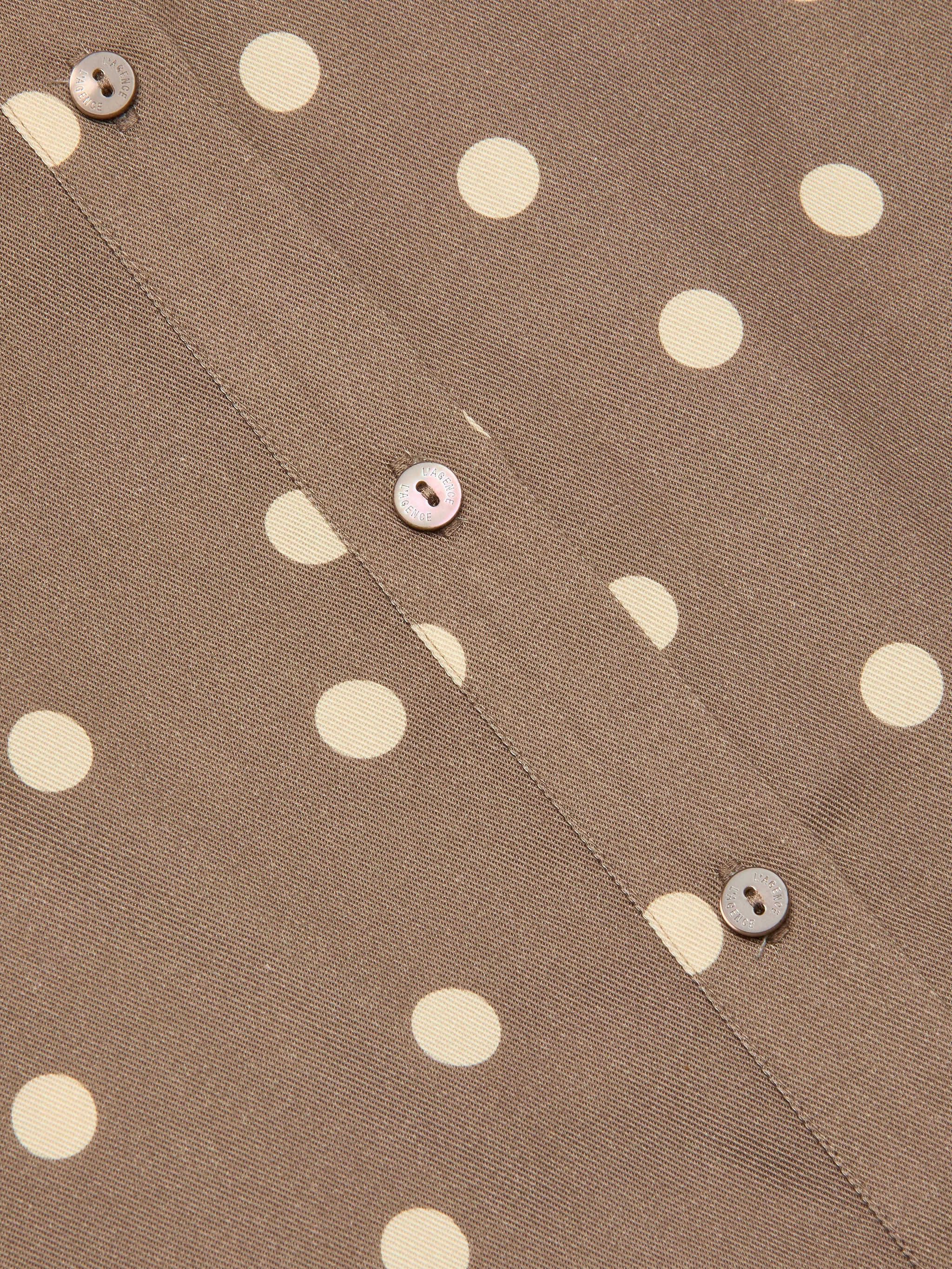 Close-up of the Ellery Button-Down Shirt in cardamom brown fabric with cream polka dots, featuring three light brown buttons sewn along a seam.