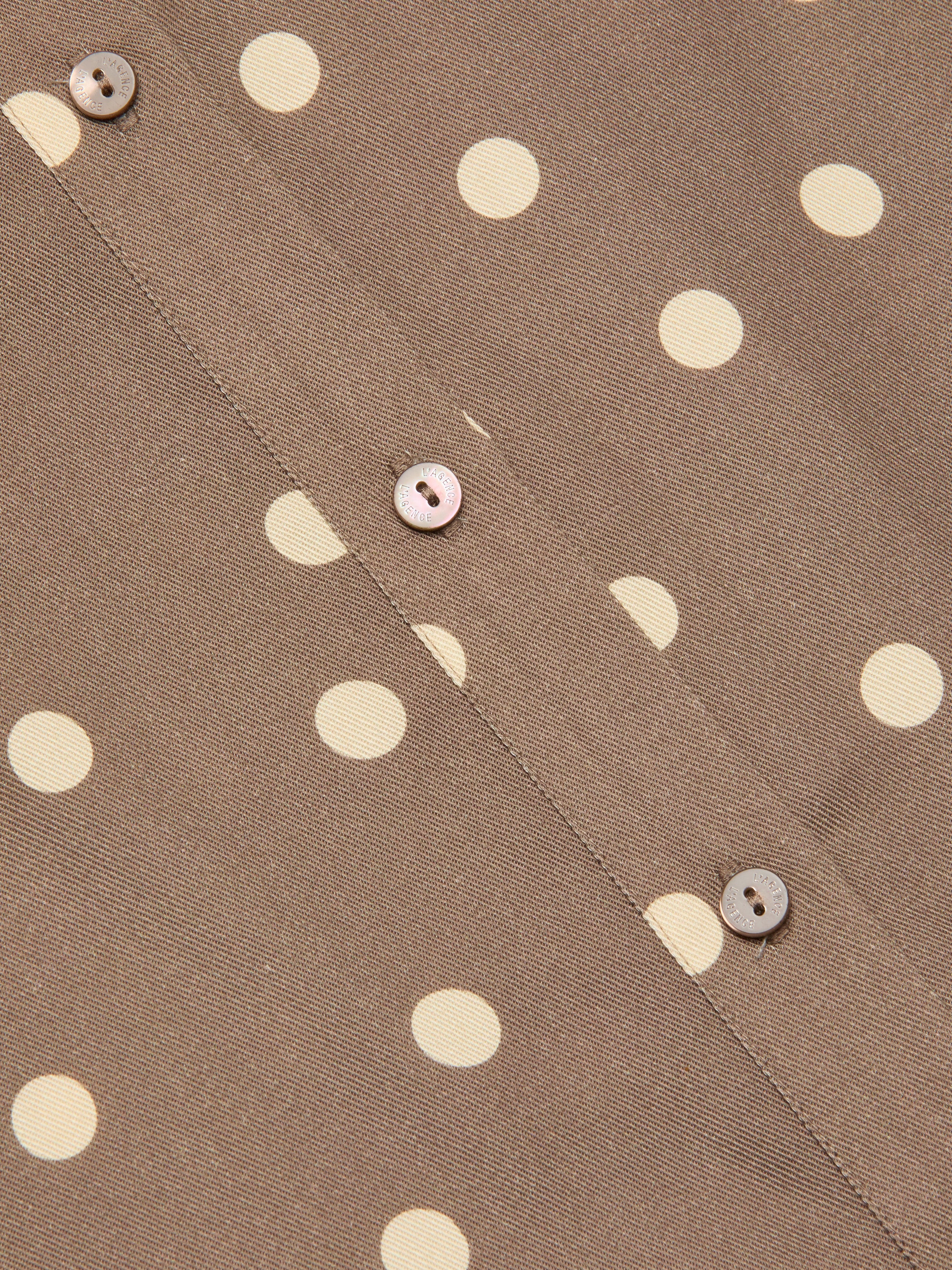 Close-up of the Ellery Button-Down Shirt in cardamom brown fabric with cream polka dots, featuring three light brown buttons sewn along a seam.