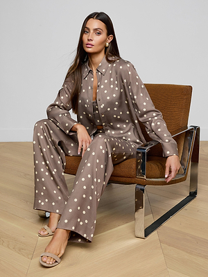 Woman in a polka dot outfit sitting on a modern chair with a neutral background