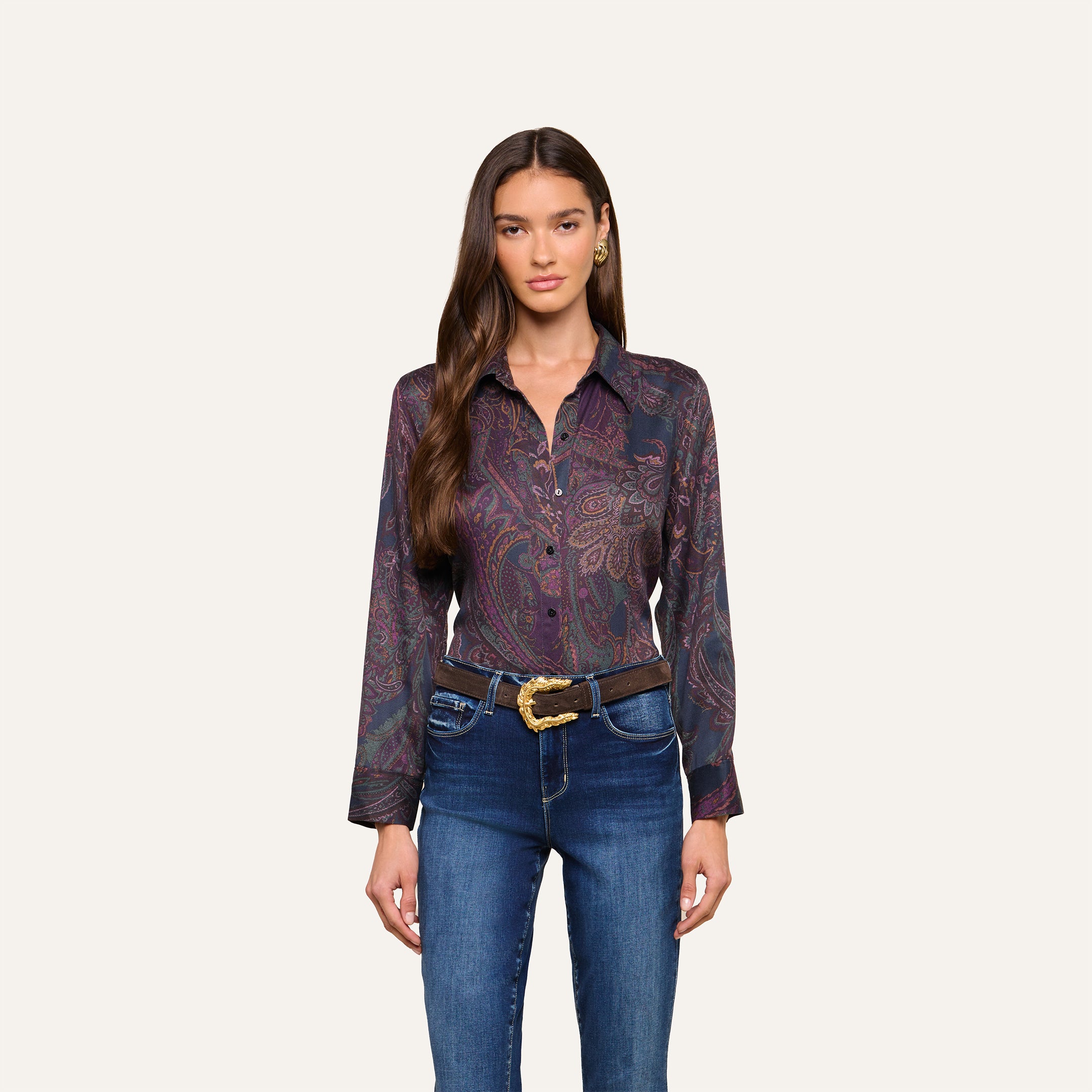 Woman with long brown hair wearing the Ellery Button-Down Shirt, tucked into blue jeans with a decorative belt, standing against a plain light background.