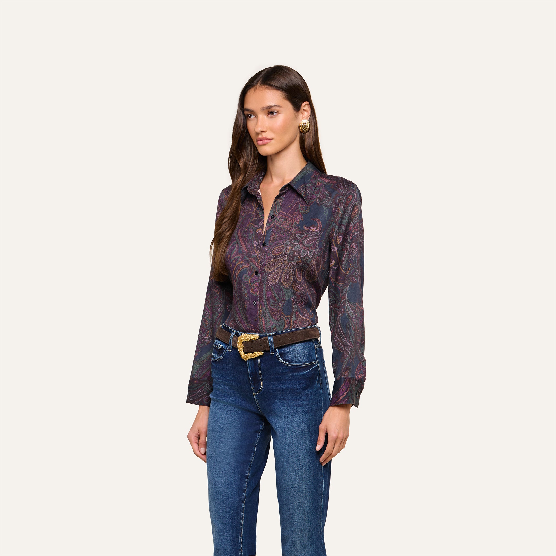 A woman with long brown hair wears the Ellery Button-Down Shirt, styled with blue jeans and a black belt, standing against a plain light background.