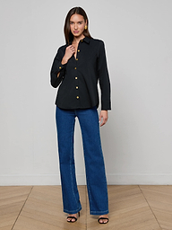 Wearing the Ellery Button-Down Shirt in black and a pair of blue jeans, a woman poses against a plain white background with one hand near her collar and the other resting by her side.