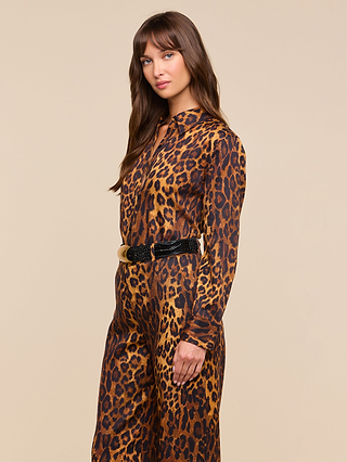 A woman with long brown hair wears the Ellery Blouse, styled in a relaxed fit, standing against a plain beige background and looking toward the camera with a neutral expression.