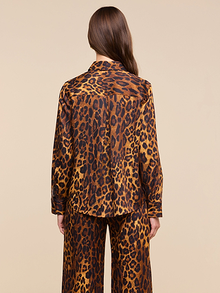 A person with long brown hair is shown from the back against a plain beige background, wearing the relaxed fit Ellery Blouse in a leopard print paired with matching pants.