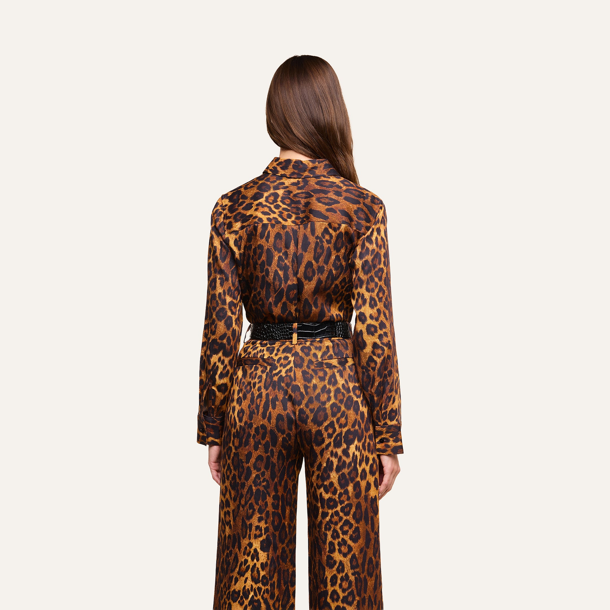 A person with long brown hair faces away, wearing the Ellery Blouse—a matching leopard print, relaxed fit top—paired with coordinating pants and belted at the waist, set against a plain light background.