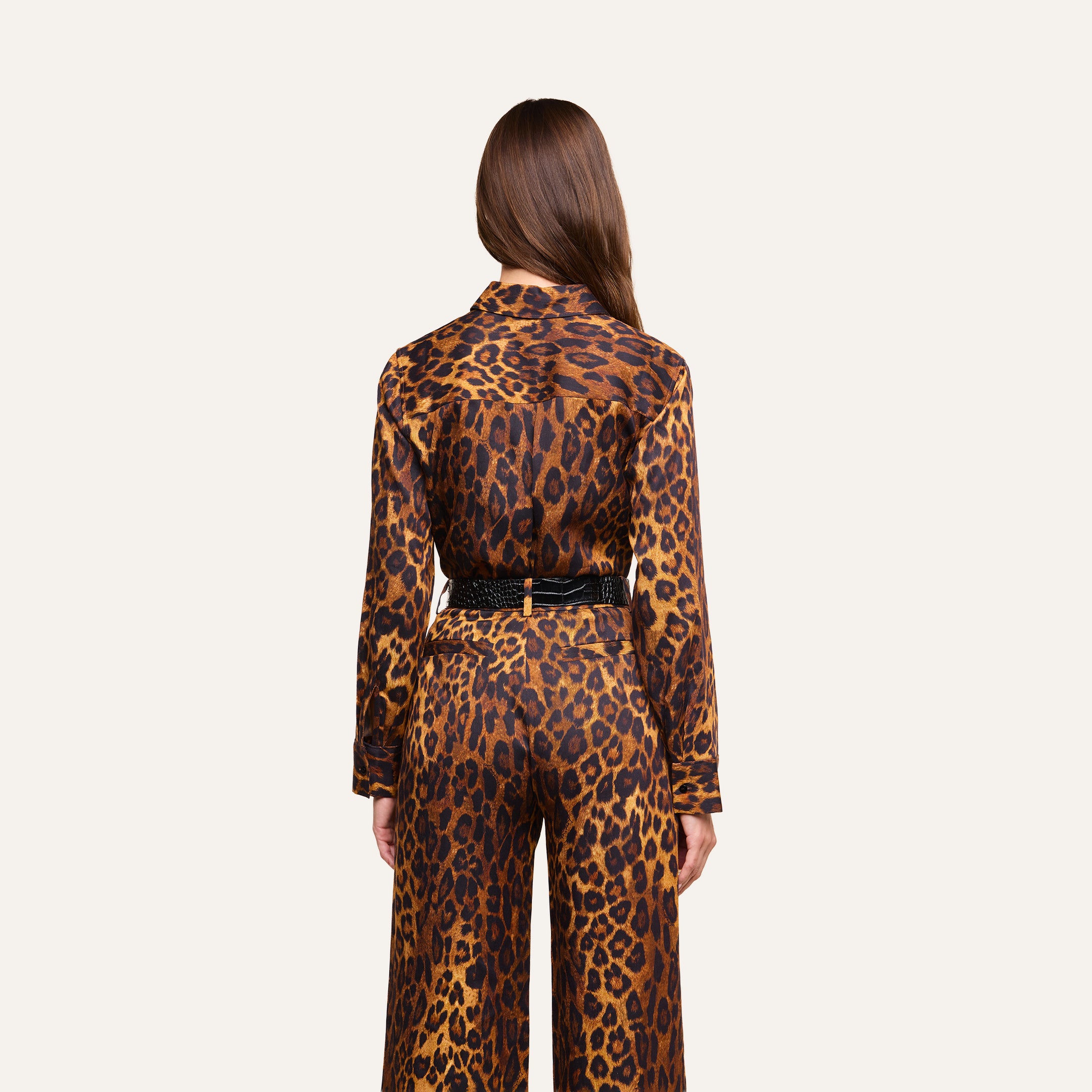 A person with long brown hair faces away, wearing the Ellery Blouse—a matching leopard print, relaxed fit top—paired with coordinating pants and belted at the waist, set against a plain light background.