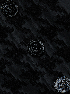 Close-up of the Maylin Houndstooth Top by L'AGENCE: black chenille jacquard with a subtle houndstooth pattern, accented by four glossy black buttons embossed with intricate crest designs.