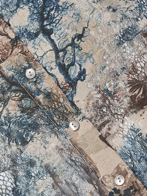 Close-up of the Maia Printed Lace Blouse by L'AGENCE, featuring a textured fabric with a nature-inspired blue, brown, and beige print, subtle snakeskin pattern reminiscent of Western toile, and white buttons sewn along the seam.