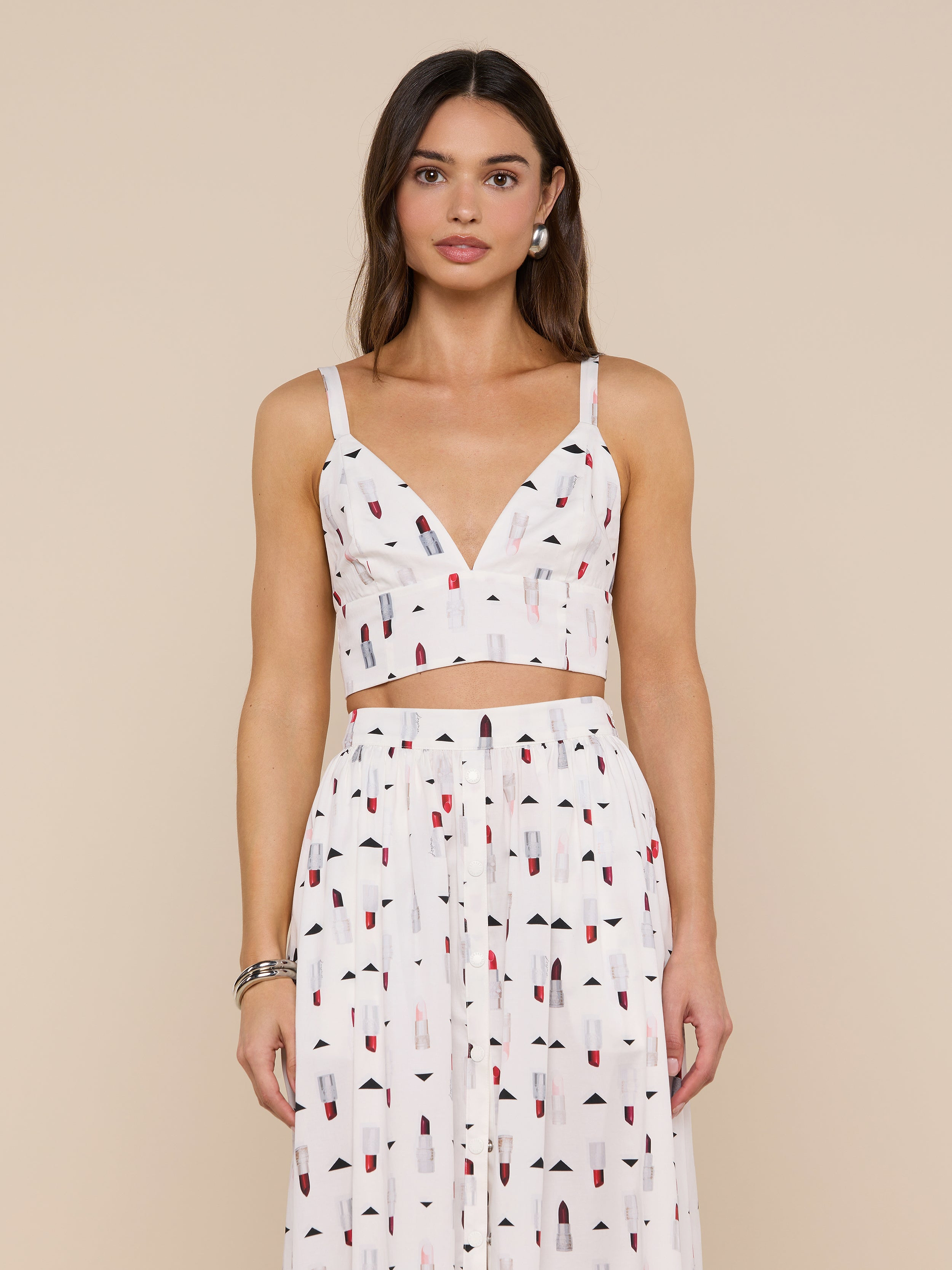 Woman wearing the Kaori Bralette Top, a white sleeveless bralette paired with a matching high-waisted skirt featuring a colorful lipstick print, standing against a plain light background.