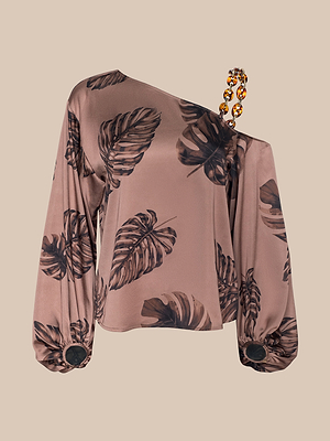 The Asami Chain One-Shoulder Blouse features brown satin with a black leaf print, an asymmetrical neckline, a chunky tortoise shell chain strap, and long sleeves with wide cuffs embellished by black circular accents.
