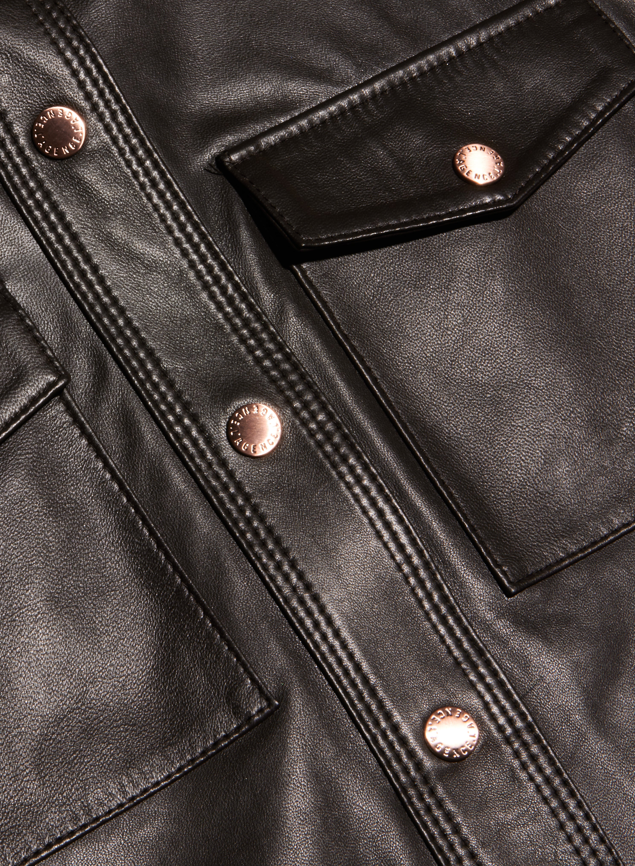 Close-up of the Avina Leather Shirt in lightweight black leather, detailed with shiny copper buttons, visible stitching, two front pockets, and a flap accent.