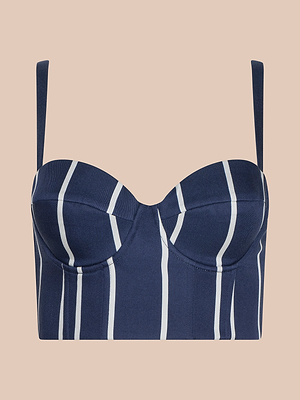Le bustier Sonya est un haut marine avec de fines rayures verticales blanches, des bonnets à armature et des bretelles réglables, présenté sur un fond pêche pâle.