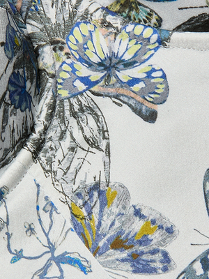 Close-up of the Sonya Silk Bustier, featuring detailed blue butterfly prints and delicate floral elements on white silk. This artistic design is perfect for an elegant, standout look.