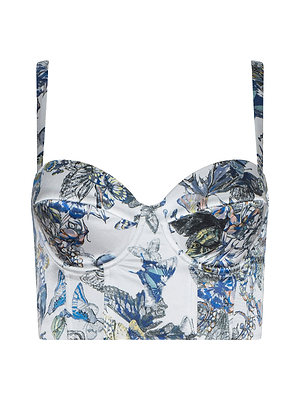 The Sonya Silk Bustier is a cropped, fitted top with thin straps, made from silk and showcasing a blue butterfly print with yellow and green floral accents on a white background.
