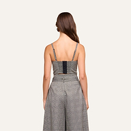 A woman with long brown hair stands facing away, wearing the sleeveless Sonya Bustier with built-in support and matching high-waisted pants against a plain light background.