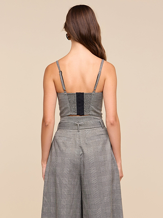 A woman with long brown hair is shown from the back, wearing the Sonya Bustier in gray plaid with adjustable straps and matching high-waisted wide-leg pants against a beige background.