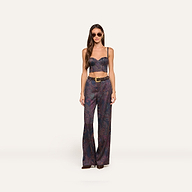 A woman wearing sunglasses and the Sonya Bustier—a navy paisley top with built-in support—paired with matching high-waisted, wide-leg pants featuring a belt. She stands facing forward against a plain light background.