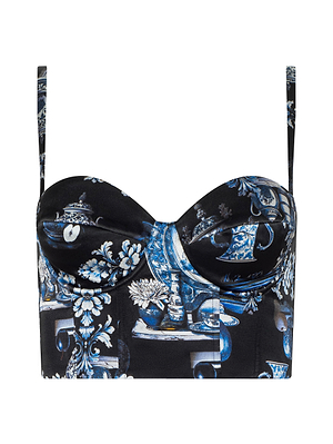 The Sonya Silk Bustier by L'AGENCE is a cropped silk charmeuse top with thin straps, structured cups, and a fitted silhouette, featuring a blue and white porcelain print on black.