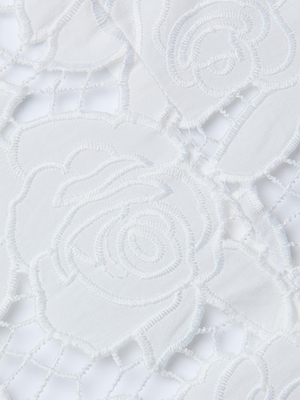 Close-up of the Sonya Bustiers white lace fabric, showcasing an intricate floral rose pattern with embroidered edges and a mesh background, echoing delicate cotton eyelet details.