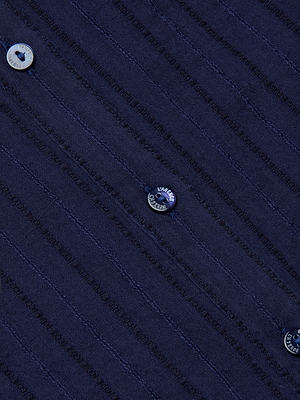 Close-up of the Kiera Blouse in navy blue cotton-blend jacquard fabric, featuring subtle vertical lines and round, shiny buttons for a bohemian touch.