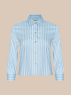 The Fawn Beach Print Shirt features light blue and white vertical stripes, crafted from organic cotton with long sleeves, a pointed collar, and gold buttons, shown on a plain beige background.