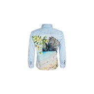 The Fawn Beach Print Shirt is a blue and white striped shirt made from organic cotton, showcasing a scenic beach, lemon tree, and rock formation print on the back.