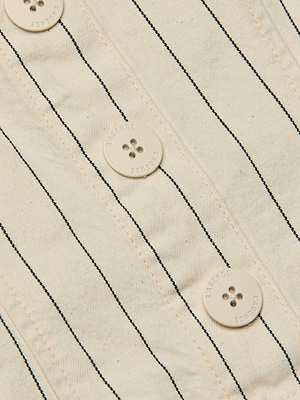 Close-up of the cream-colored cotton twill Saga Top, featuring thin nautical stripes and three white buttons embossed with “LENOSE.”.