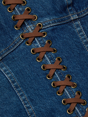 Close-up of blue stretch denim on the Nayeli Corset Top by L'AGENCE Sale, featuring vegan suede laces through metal eyelets in a corset-style crisscross, with visible stitching outlining the seams.