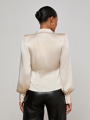 A woman with her hair in a neat bun is shown from the back, wearing the L'AGENCE Bernice Satin Wrap Blouse and black leather pants against a plain light background.