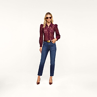 A woman wearing sunglasses, the Anita Lace Blouse in burgundy, blue jeans, a brown belt, and burgundy heels stands against a plain white background.