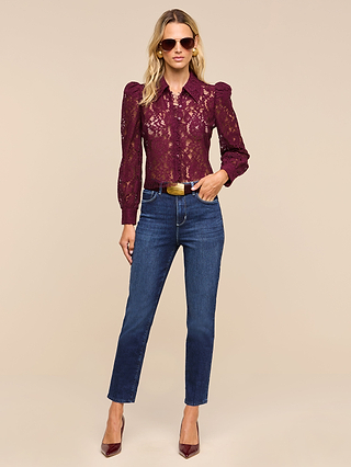 Wearing the Anita Lace Blouse, a woman styled in sunglasses, blue jeans, and burgundy heels stands confidently against a beige background.