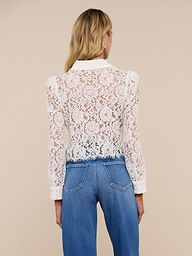 A woman with long blonde hair, wearing blue jeans and the Anita Lace Blouse, is shown from the back against a plain light background.