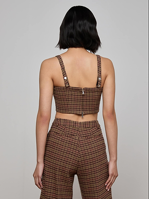 A person with short black hair is shown from behind, wearing the L'AGENCE Tiffany Corset Top in brown and red plaid. The background is plain and light gray.