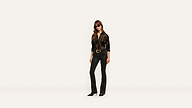 A woman wearing sunglasses, a black patterned sheer button-down shirt, and black flared pants with a gold-accented belt.