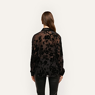 Back view of a person wearing a sheer black Laurent Velvet Blouse with a crinkle velvet floral pattern in a relaxed, button-down fit.